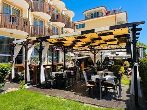a restaurant with tables and chairs under a pergola at Ivian Family Hotel in Ravda