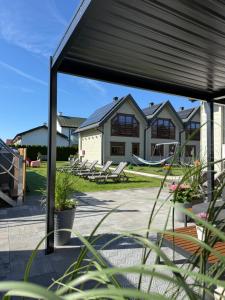 a patio with a black cover and a house at Domki Gala- blisko plaży, basen z podgrzewaną wodą , sauna , parking in Grzybowo