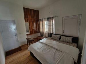 a bedroom with a bed and a table and a chair at MP Residency Homestay in Munsyari