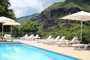 a pool with chairs and umbrellas next to a mountain at Vardzia Resort in Vardzia