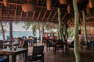 a restaurant with tables and chairs and a view of the ocean at Mambo’s hotel Arugam Bay in Pottuvil