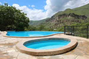 two large swimming pools with mountains in the background at Vardzia Resort in Vardzia
