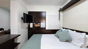 a bedroom with a bed with a flat screen tv at Baviera Studio Canela in Canela