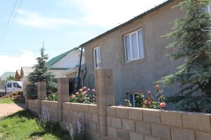a house with a retaining wall and flowers at Khan Dobo in Bokonbayevo