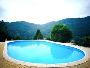 a large blue swimming pool with mountains in the background at Vale de Azereiros Apartamentos - Alojamento no Gerês in Geres