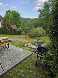 a backyard with a grill and picnic tables and benches at Rodzinny dom w Rożnowie Duży Ogród i Zabawki in Rożnów