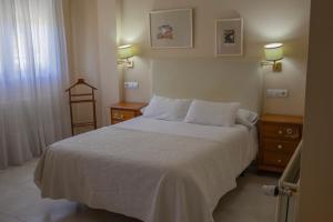 a bedroom with a white bed and two night stands at Hotel La Brañina in Villablino