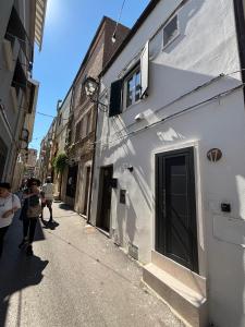 a woman walking down a street next to a white building at Bordo piazza in Vasto