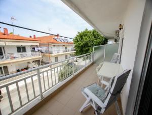 a balcony with a white chair and a table on it at Emotion Apartments in Asprovalta