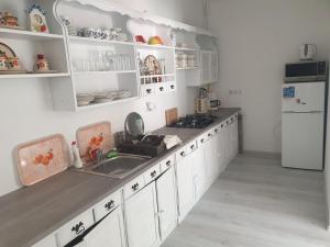 a kitchen with white cabinets and a sink and a refrigerator at La Casa Vendégház in Bogács