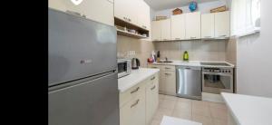a kitchen with white cabinets and a stainless steel refrigerator at Vila-kuca"Jasmin"pored rijeke i jezera in Konjic