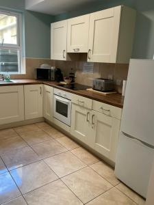a kitchen with white cabinets and a white refrigerator at Chamberlain House in Derry Londonderry