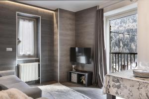 a living room with a couch and a tv and a window at Angels Home 3-AffittiPontediLegno in Ponte di Legno