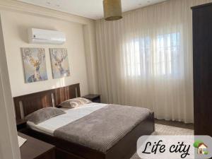 a bedroom with a bed and a large window at Life city home in 6th Of October