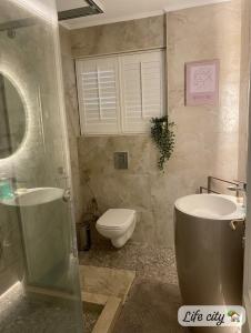 a bathroom with a toilet and a sink and a mirror at Life city home in 6th Of October +3 photos