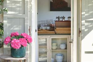 a cabinet with a vase of pink flowers on a stool at Masseria Borgo Sentinella in Torre dell'Orso