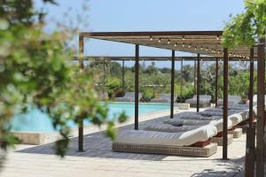 a row of lounge chairs next to a swimming pool at Masseria Borgo Sentinella in Torre dell'Orso +103 photos