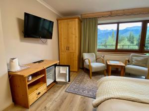 a hotel room with a bed and a television at Willa Sosna in Kościelisko