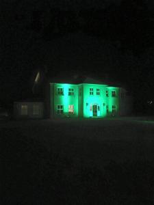 une maison blanche éclairée en vert la nuit dans l'établissement Red Gate House B&B, à Malin