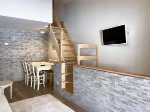 a room with a table and a tv and a brick wall at Fiocco di Neve - AffittiPontediLegno in Passo del Tonale