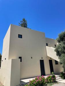 a white building with black doors and flowers at Nikos Apartments & Studios in Plakias +10 photos