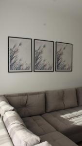 four framed pictures on a white wall above a couch at Apartman Lejla in Bjelašnica