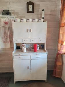a kitchen with white cabinets and cups on top of it at Metsämökki in Lohja