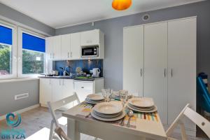 a kitchen with white cabinets and a table and chairs at Lazurowa Bryza in Poddąbie
