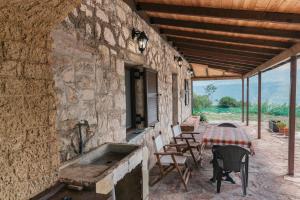 a stone building with a table and chairs on a patio at Κτήμα Βασίληγιάννη in Kouklésion