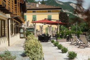 a patio with tables and chairs and an umbrella at Hotel al Dòs - Breakfast & Private SPA in Trento