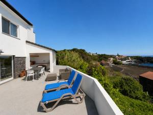 two blue lounge chairs on the balcony of a house at Pico Island Villas 38 - Private Atlantic Retreat in Santo António