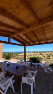 a picnic table and chairs under a wooden roof at Stazzo gallurese Li Nibbareddhi in Aglientu +11 photos