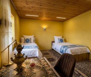 a bedroom with two beds and a table with a chair at Ecomama in Xınalıq Khinalig guest house in Xınalıq