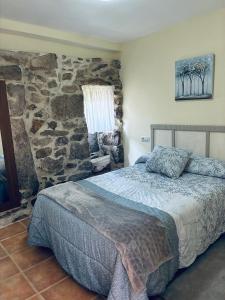 a bedroom with a bed and a stone wall at Casa Avoa María in Ourense