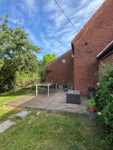 a patio with a table and chairs and a brick building at Au cochon qui rit in Flines-lès-Mortagne