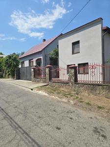 a white building with a red fence next to a street at Petite Chambre in Velyatyn