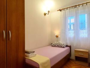 a small bedroom with a bed and a window at Apartment Josip in Primošten