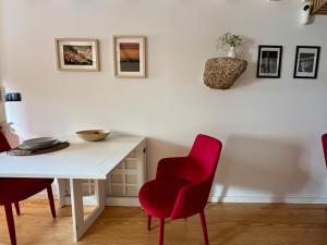 a dining room with a white table and red chairs at Casa N'Aninhas - Santar in Santar