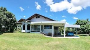 a white house with a car parked in a yard at Lamphun Garden Home in Lamphun