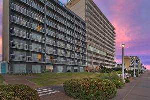 a large apartment building with a sunset in the background at SureStay Studio by Best Western Virginia Beach Oceanfront in Virginia Beach