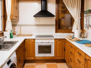 a kitchen with wooden cabinets and a stove top oven at Casa Ilera II, en el corazon de Rioja Alta 8 PAX in Casalarreina