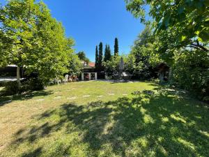 a large yard with trees and a house at VÁRLAK VENDÉGHÁZ in Siófok