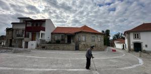a man with a cane standing in the middle of a street at Casa N'Aninhas - Santar in Santar +7 photos