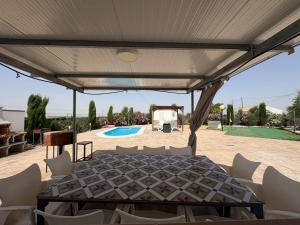 a patio with a table and chairs and a pool at CUEVA RURAL PALAPA DEL PERAL in El Charcón