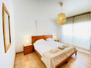 a bedroom with a bed and a table with towels on it at Aloha Burgau Guesthouse in Burgau