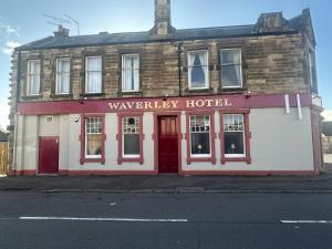 a red and white building on the corner of a street at Waverley Hotel in Bonnyrigg