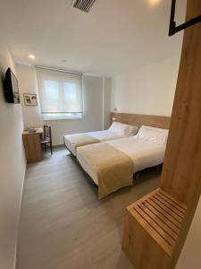 a bedroom with two beds and a table and a window at Hotel Chiquín in Tapia de Casariego