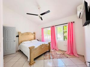 a bedroom with a bed and a window with pink curtains at HappiCasaRD & Holistic House in Sosúa +32 photos