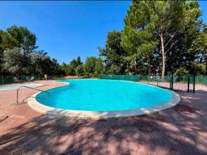a large swimming pool in a park with trees at La Parenthèse Landaise Duplex rénové avec jardin & piscine in Saint-Julien-en-Born