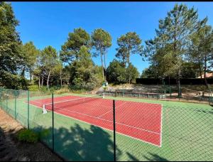 a tennis court with a net at La Parenthèse Landaise Duplex rénové avec jardin & piscine in Saint-Julien-en-Born